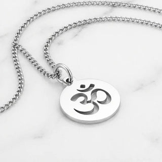 Silver necklace with a pendant featuring an Om symbol on a marble background