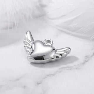 Silver heart-shaped pendant with wings on a marble surface