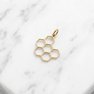 Gold honeycomb pendant on a marble surface