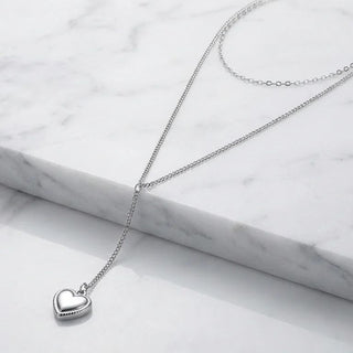 Silver heart-shaped pendant necklace on a marble surface