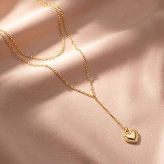 Gold heart-shaped pendant necklace on a soft pink background