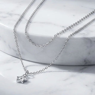 Layered silver necklaces on a marble surface