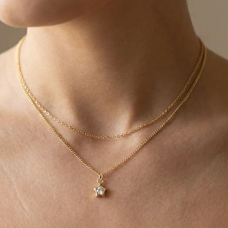 Gold necklace with a star pendant on a person's neck