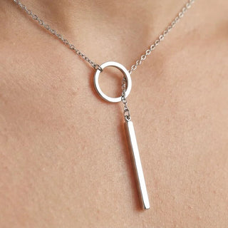 Silver necklace with a circular pendant and a vertical bar on a neck
