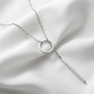 Silver necklace with a circular pendant and a bar on a white fabric background