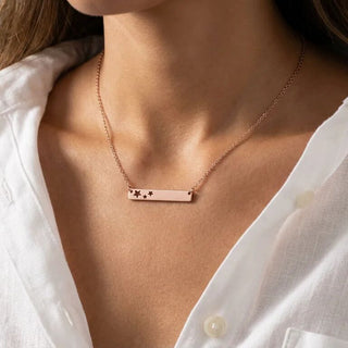 Rose gold necklace with star details on a person wearing a white shirt.