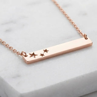 Rose gold necklace with star charms on a light gray background