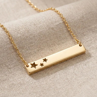 Gold necklace with star-shaped pendants on a beige fabric background