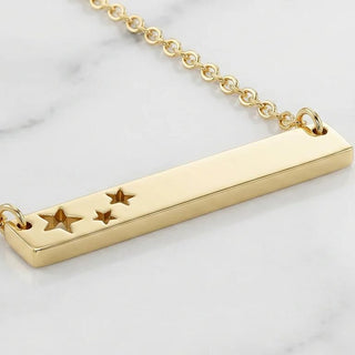 Gold necklace with star designs on a light background