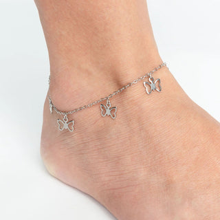 Silver butterfly anklets on a person's ankle against a white background