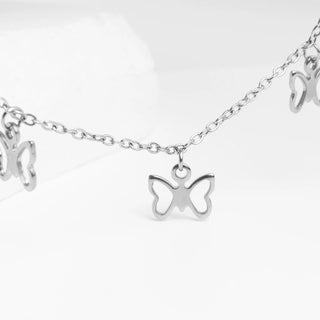 Silver butterfly charm necklace on a white background