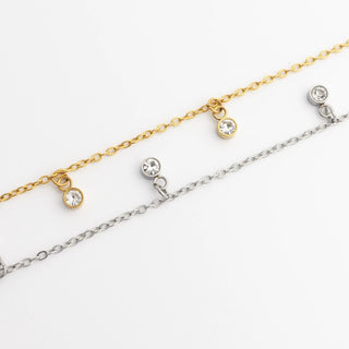 Two gold and silver anklets with small round stones on a white background