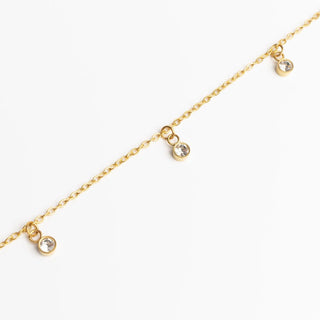 Gold anklet with small round crystals on a white background