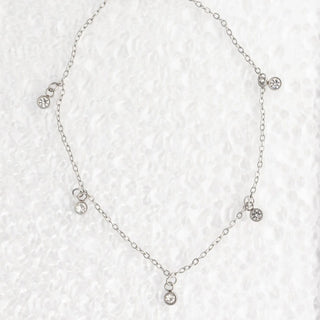 Silver necklace with small crystals on a textured white background