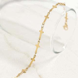 Gold bracelet with cross designs on a white surface