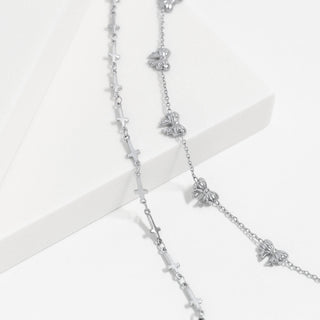Silver necklace with bow and cross pendants on a white background