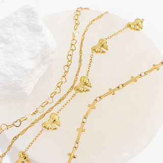 Two gold necklaces with floral and cross designs on a white background