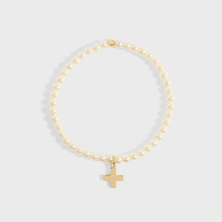 Gold bracelet with a cross charm on a light gray background