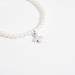 Pearl bracelet with a silver cross charm on a white background
