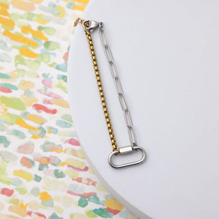 Two chain straps, one gold and one silver, on a colorful patterned surface.