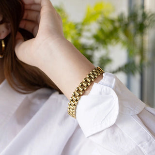 Gold bracelet on a person's wrist with a blurred background
