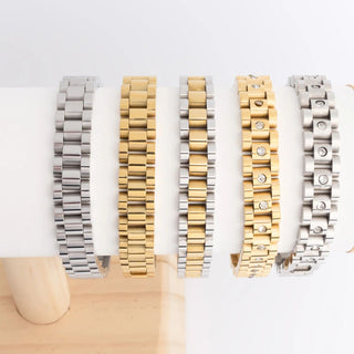 Set of five metal bracelets in different designs on a white surface.
