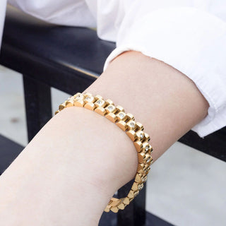 Gold bracelet on a person's wrist with a blurred background