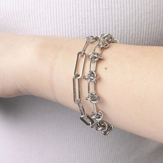 Silver chain bracelet on a wrist against a light background