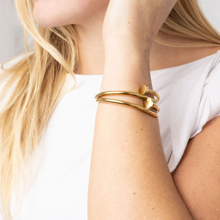 Gold bracelet on a person's wrist with a plain background