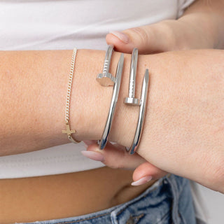 Silver bracelet on a wrist with a plain background