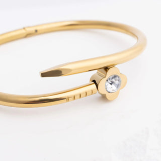 Gold bangle with a clear gemstone on a white background