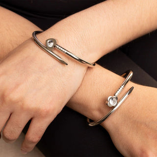 Silver bangle with a small gemstone on a wrist against a dark background