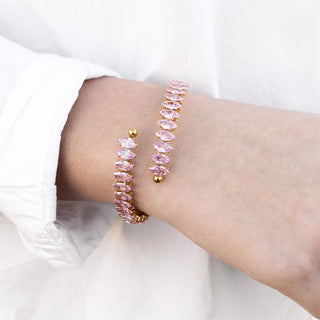 Pink beaded bracelet with gold accents on a wrist against a white background