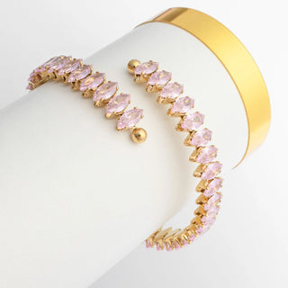 Gold bracelet with pink stones on a white surface