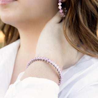 Close-up of a person wearing a pink beaded bracelet and earrings.