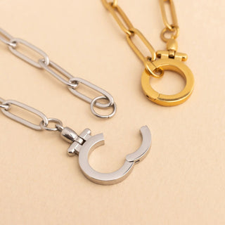 Two necklaces, one gold and one silver, on a beige background