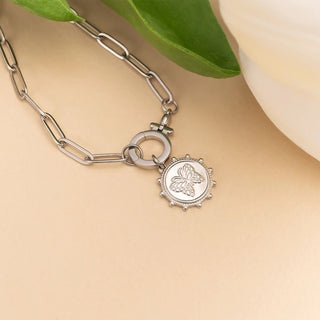 Silver bracelet with a butterfly charm on a beige background