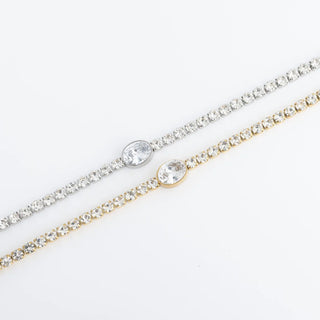 Two gold and silver bracelets with clear stones on a white background