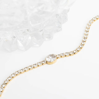 Gold bracelet with a central gemstone on a white background