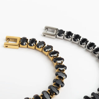 Bracelet with black gemstones and gold and silver clasps on a white background