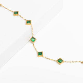 Gold necklace with green gemstones on a white background