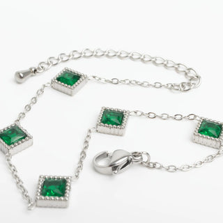 Silver bracelet with emerald green gemstones on a white background
