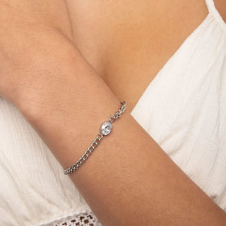 Silver bracelet with a clear gemstone on a wrist against a white background