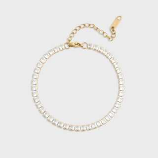 Gold bracelet with clear gemstones on a light gray background