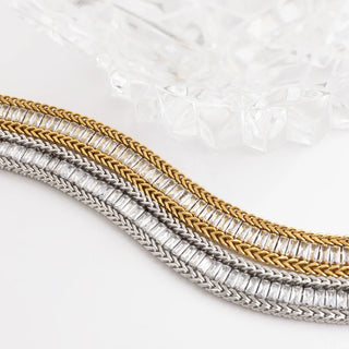 Three braided necklaces in gold and silver on a textured white background