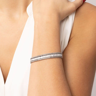 Silver bracelet on a person's wrist with a neutral background