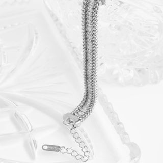 Silver chain necklace on a textured white surface