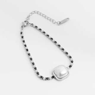 Silver bracelet with heart-shaped clasp and black beads on a white background