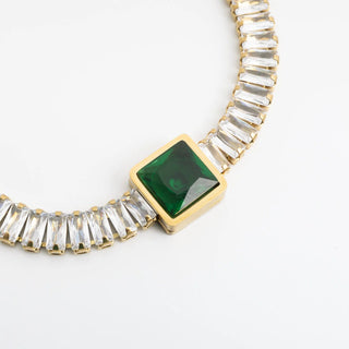 Necklace with green gemstone and clear stones on a white background