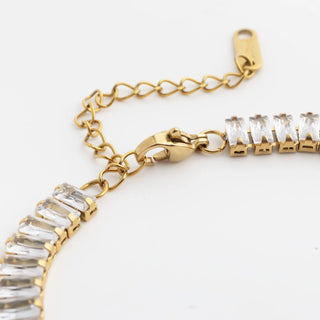 Gold bracelet with clear gemstones on a white background